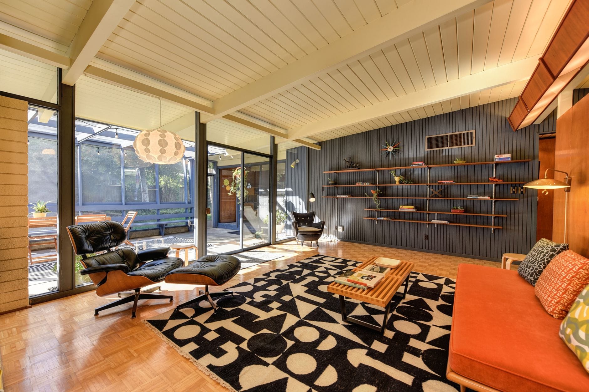 Salon mid-century modern z fotelami, półkami i światłem dziennym